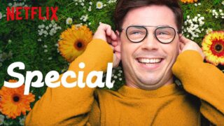 White man wearing glasses, smiling, laying on grass with around flowers him, promoting Netflix series 'Special'