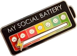 A social battery pin with a colour gradient scale that changes from red to green to indicate your current social energy level. The colours correspond to different emoji faces that represent different moods - from tired or drained (red) to energised and happy (green). You can adjust the indicator to match your current mood with a lightning bolt icon that selects the appropriate level of your 'social battery'. Above the scale you can read "My social battery" in white font on a black background.